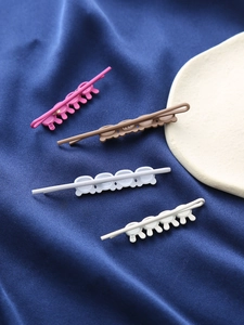 Détail de barrettes à cheveux mates sur plateau céramique et tissu de soie bleue