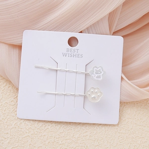 Set de pinzas para el cabello con gato y garra blanca sobre tarjeta de regalo rosa