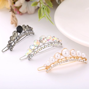 Three elegant hair clips with sparkling rhinestones and pearls displayed on a white tray