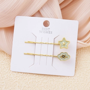 Detalle de pinzas para el pelo doradas con dijes de estrella y nube en cartulina