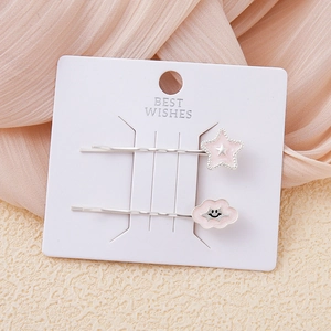 Detalle de pinzas para el pelo con estrella rosa y nube en tarjeta de regalo blanca