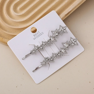 Pair of silver star-shaped hair clips with sparkling rhinestones on a display card