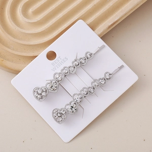 Close-up of sparkling heart-shaped rhinestone hair clips on a white display card