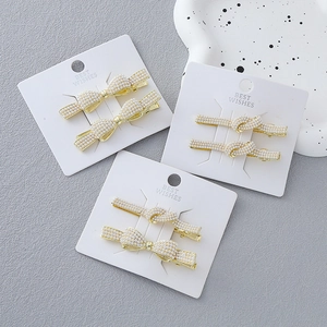 Elegant 6-piece pearl bow hair clip set with gold finish on minimalist display cards