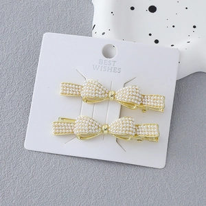 Elegant gold bow hair clips set with white pearls on display card for women