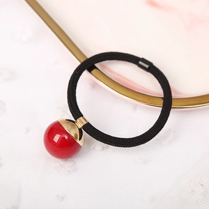 Minimalist elastic hair tie with red pearl pendant on elegant marble and lace tray