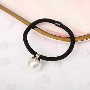 Elegant black elastic hair tie with a large white pearl bead on marble tray