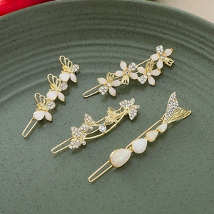 Elegant four-piece gold hair clip set with butterfly and flower designs in a ceramic tray