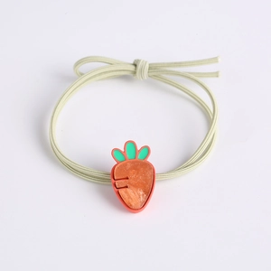 Détail d'un élastique à cheveux vert avec un joli charm de carotte orange translucide