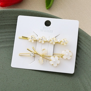 Détails de barrettes florales avec perles et strass sur une carte de présentation