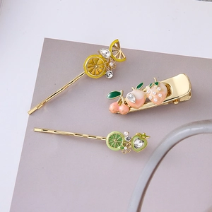 Dettaglio di 3 fermagli per capelli a tema frutta con smalto e accenti di perle