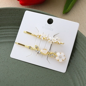 Détail de barrettes dorées ornées de perles blanches, strass et motifs floraux fins