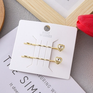 Elegant gold-tone hair clips with heart-shaped crystals on card backing