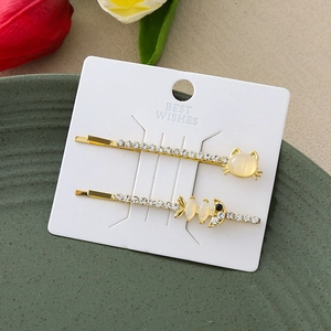 Détail de barrettes dorées avec motifs chat et arête de poisson et pierres d'opale jaune