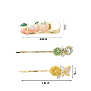 Dettaglio macro di fermagli per capelli ciliegia e limone con perle e strass dorati