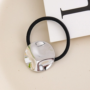 Detail of minimalist black hair tie featuring a round silver hammered metal ornament