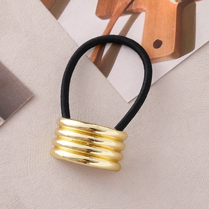 Detail eines minimalistischen Gold-Metallrohr-Charms am schwarzen Haargummi für Damen