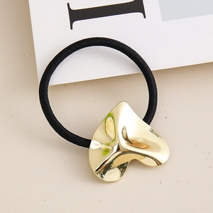 Minimalist elastic hair tie with a gold heart-shaped metal charm on a neutral background
