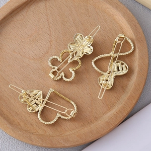 Detail of golden alloy hair clips with heart and flower shapes on a wooden tray