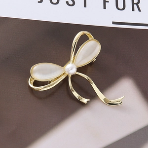 Barrette nœud doré avec pierres opales blanches et perle centrale sur fond de magazine chic