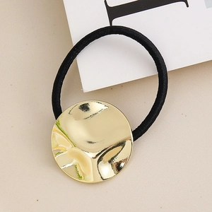 Close-up of black elastic hair tie with a textured gold metallic wave disk charm