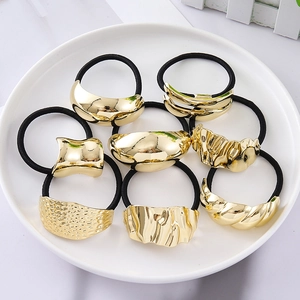 Set of 8 minimalist elastic hair ties with irregular gold metal charms on white plate
