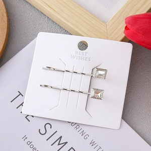 Detail of silver hair clips with square crystals on a white card display with tulip