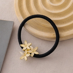 Détail de l'élastique à cheveux noir orné de trois fleurs en opale crème avec bordure dorée