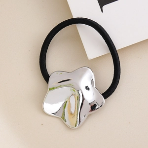 Detailed close-up of a silver star charm on a black elastic hair tie over a beige tray