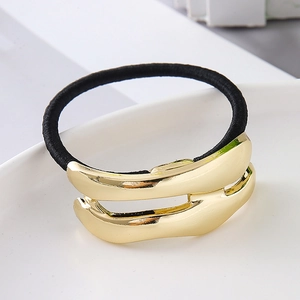 Macro detail of elastic hair tie featuring a golden double-layered metallic curved ornament