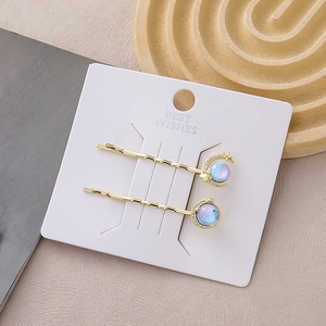 Detail of galaxy themed hair clips featuring a crescent moon and a purple iridescent planet