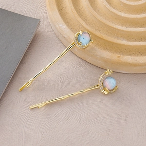 Detailed close-up of celestial hair clips with moon and star motifs on a textured tray