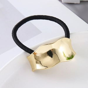 Close-up of golden wavy metal decoration on high-elastic black hair tie with mirror finish