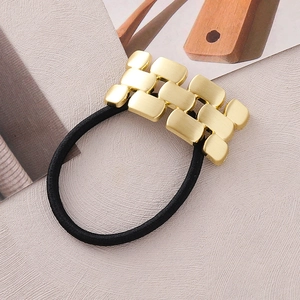 Detail view of the matte gold textured metallic chain links on a black elastic hair tie