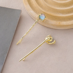 Detailed close-up of golden celestial hair clips featuring moon and blue stone star designs