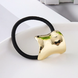 Close-up of black elastic hair tie with curved gold metal plate on white ceramic plate