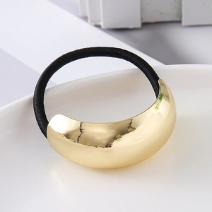 Detailed close-up of large golden curved metal element on elastic hair tie with mirror finish
