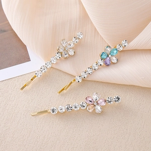 Detalle de tres pinzas para el cabello con flores y diamantes sobre fondo de seda beige