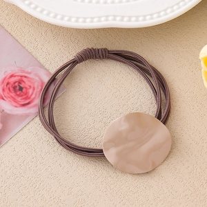 Detail of dark brown multi-strand elastic hair tie with irregular resin charm