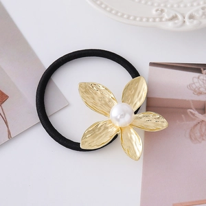 Dettaglio dell'elastico per capelli con fiore dorato martellato e perla su sfondo bianco