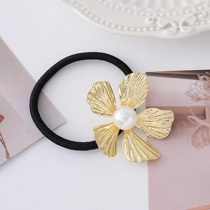 Dettaglio di elastico per capelli nero con fiore dorato e perla bianca