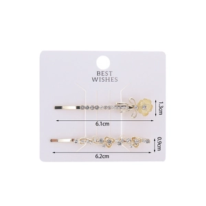 Detailed view of two gold flower hair clips with sparkling rhinestones and resin petals