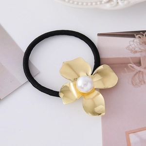 Dettaglio dell'elastico per capelli con fiore dorato e grande perla bianca centrale