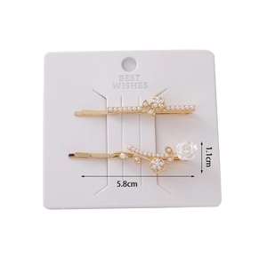 Detail view of 5.8cm gold butterfly hair clips with white rose and pearls on card
