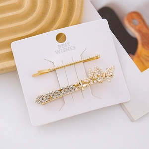Macro view of gold butterfly hair clips with pearls and rhinestones on card
