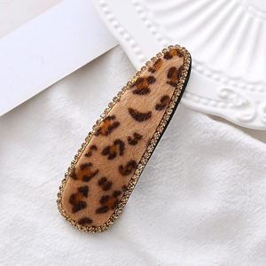 Detailed close-up of velvet leopard print hair clip with sparkling yellow rhinestones