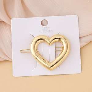 Polished gold heart hair clip for women with elegant metallic finish on display card