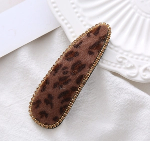 Macro shot of leopard print velvet hair clip with sparkling rhinestones on the edge