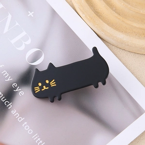 Cute black cat acrylic hair clip with golden facial details on a magazine background