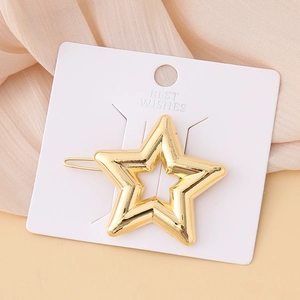 Detail of a minimalist gold star hair clip with hollow design on its retail display card